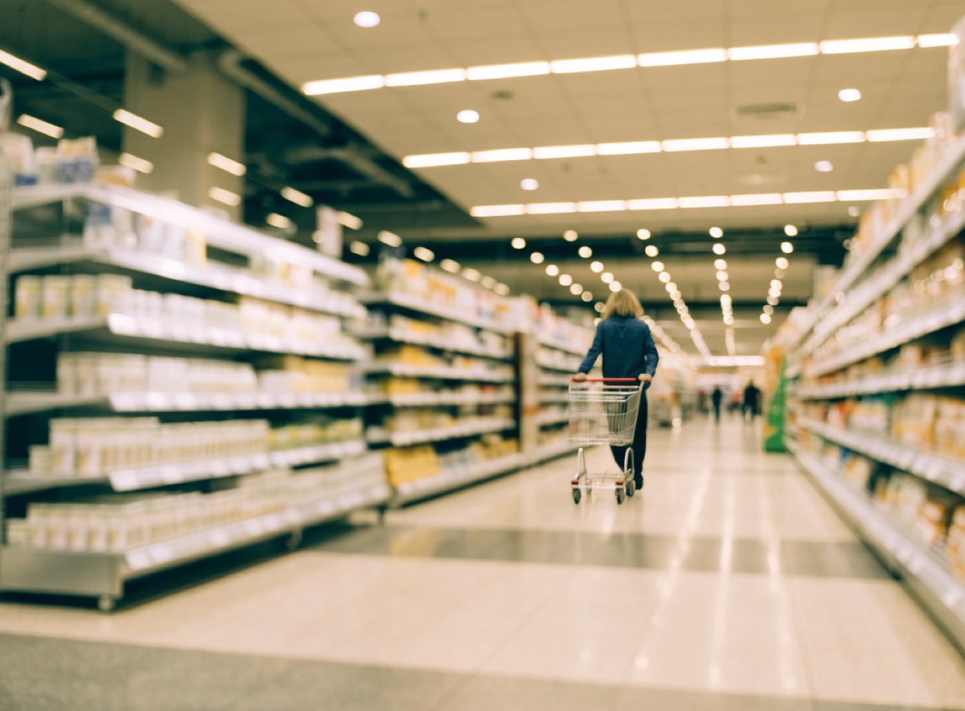A shopper in a bright modern supermarket aisle